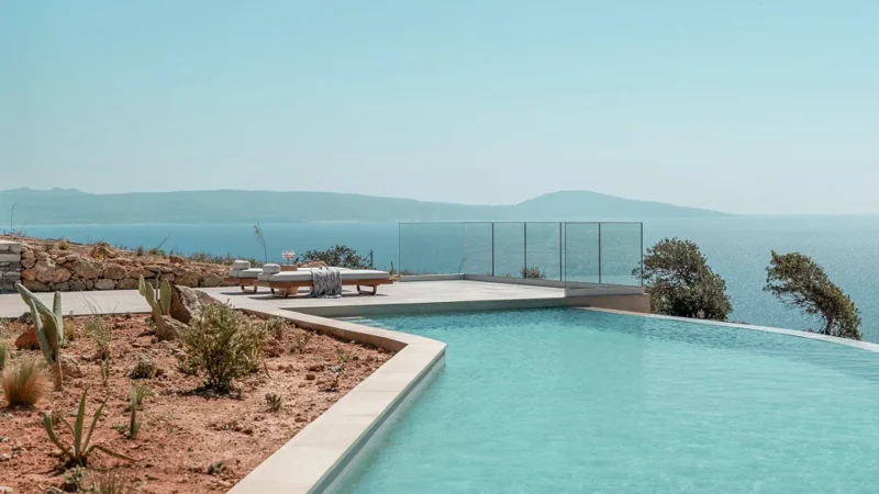 The turquoise infinity pool at Villa Anaktoron with sun loungers and distant sea views