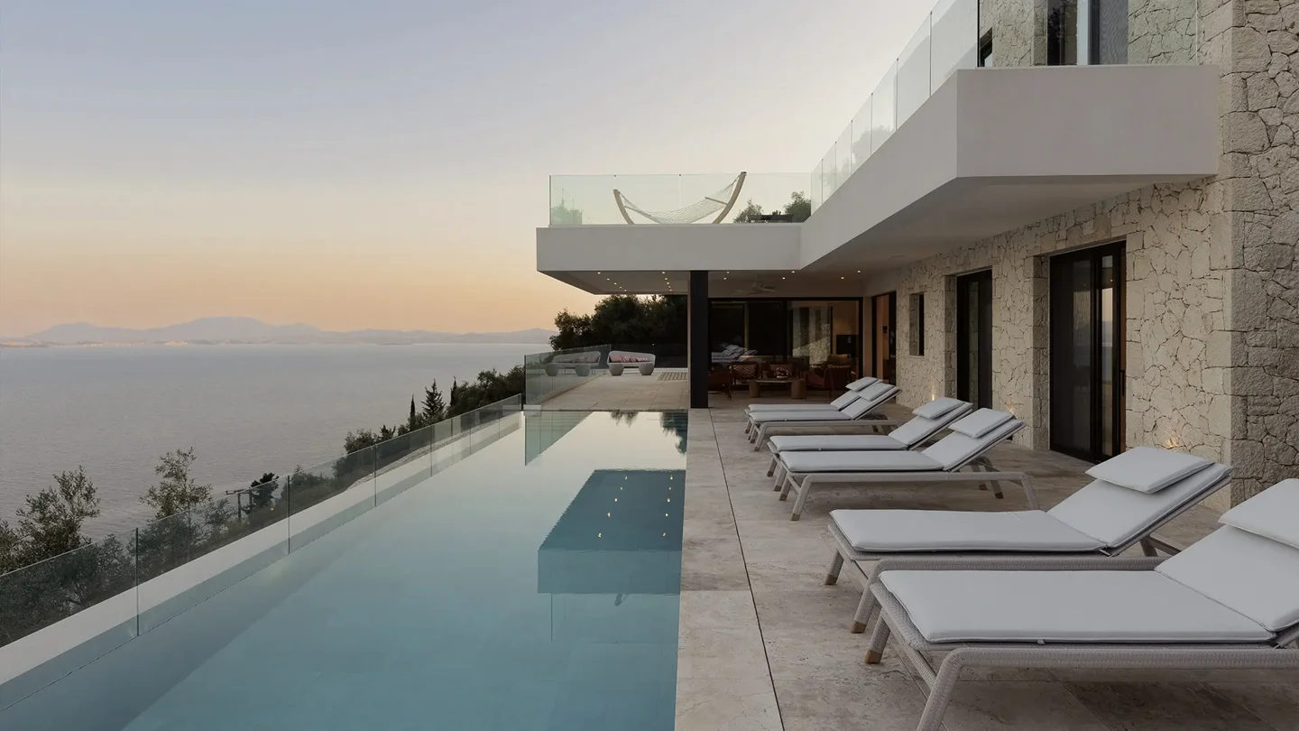 The infinity pool and stone architecture of Villa Sea You in Corfu, overlooking the sea at dusk
